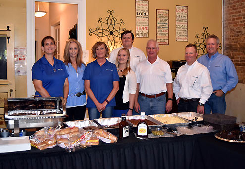 Image of eight people standing in front of food table.